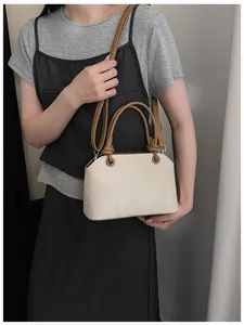 Vue détaillée d'un sac à main crème élégant avec des poignées marron sur mannequin