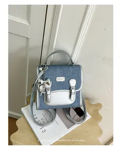 Vista detallada de una mochila vaquera elegante con adornos plateados y placa de logo metálica