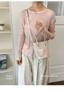 Elegant woven mini bucket bag in soft pink shown in a lifestyle model setting