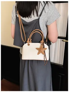 Gros plan d'un sac bandoulière en toile avec un charmant détail d'étoile brune.