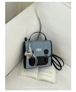 Mochila retro de mezclilla azul y cuero negro con un colgante decorativo y elegante