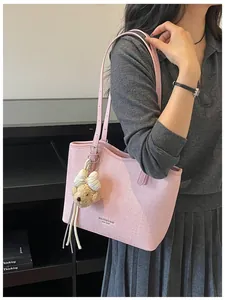 Detailed view of a pink textured tote bag with a cute bear charm for commuting.
