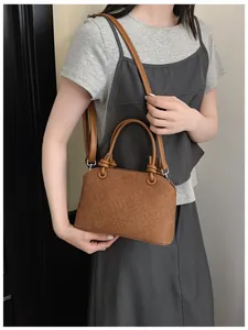 Detailansicht der stilvollen braunen Handtasche mit Doppelgriffen und Gurt