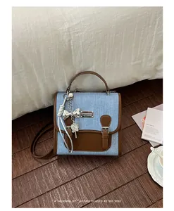 Mochila elegante de mezclilla y cuero para mujer con un dije de piruleta plateado