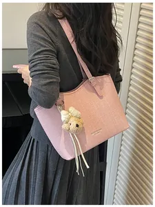 Detailed view of stylish pink textured tote bag with a cute teddy bear charm accessory