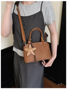 Sac à main marron texturé avec breloque étoile présenté sur un mannequin réel.