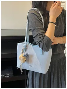 Elegant light blue textured tote bag with a cute bear charm for daily commuting.
