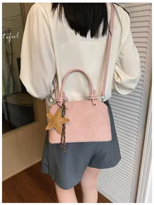 Detailansicht einer rosa Beuteltasche mit Sternanhänger, von einem Model getragen.