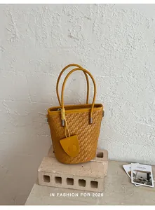 Detailed view of a yellow woven bucket bag featuring elegant top handles and fine textures.