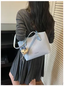 Light blue textured tote bag shown on a model's shoulder in a lifestyle setting.