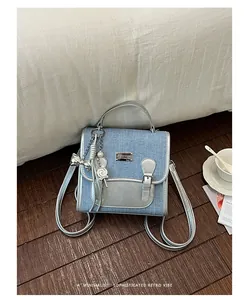 Detalle de mochila de tela vaquera y cuero plateado con adornos