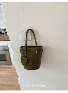 Detailed shot of an olive green woven bucket bag hanging on a minimalist wall