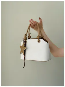Sac seau blanc texturé avec poignées nouées marron et breloque étoile à la main