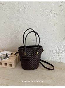 Detailed view of a dark brown woven bucket bag on a minimalist stone background