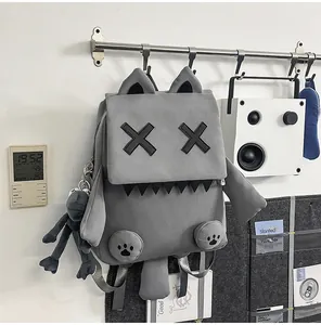 Cute grey monster backpack with X-shaped eyes and ears detail in a lifestyle setting