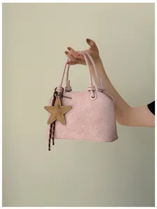 Détail d'un sac seau rose texturé avec un pendentif décoratif en forme d'étoile.