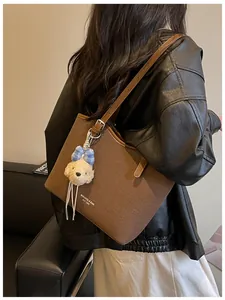 Detailed view of a large brown commuter tote bag with a cute teddy bear charm charm