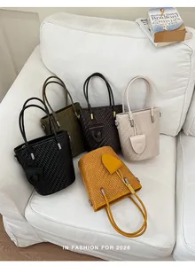 Detailed view of fashionable woven bucket bags in various colors on a white sofa
