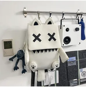 Detailed view of white monster backpack with cat ears and X eyes hanging on wall