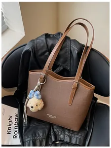 Detailed view of a brown textured tote bag with a cute plush bear charm