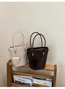 Detail shot of elegant woven bucket bags in beige and brown on a wooden shelf