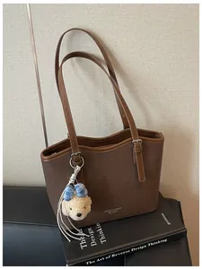 Close-up detail of the brown textured faux leather tote bag with a cute puppy charm accessory