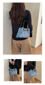 Detailed view of light blue denim bucket bag with metal buckle and star charm.