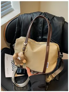 Vue détaillée du sac cabas en nylon kaki avec un charm mignon sur fond de veste en cuir noir
