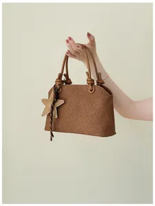 Vue détaillée en gros plan du sac à main marron texturé avec pendentif étoile mignon