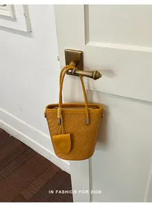 Detailed view of a yellow woven bucket bag hanging on a vintage brass door handle.