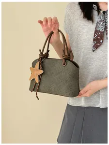 Vue détaillée d'un sac à main olive texturé avec poignées nouées et charme d'étoile