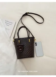 Woven leather bucket bag with top handle and adjustable strap for women, elegant brown.