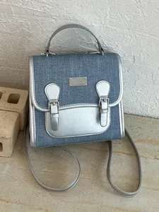 Mochila moderna de mezclilla azul para mujer con ribete metálico plateado y hebillas