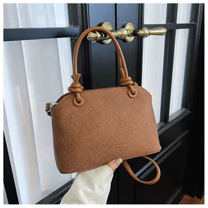 Vue détaillée sac à main en cuir texturé marron avec poignée à nœud élégante