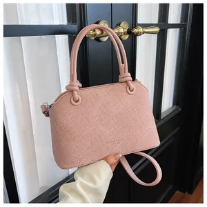 Détail d'un sac à main rose texturé avec poignées nouées et fond de porte élégant