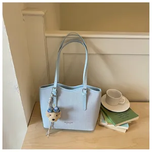 Detailed view of light blue fabric tote bag with leather straps and a cute bear charm