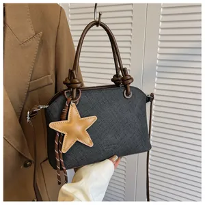 Vue détaillée d'un sac à main gris foncé texturé avec charm étoile et anses brunes
