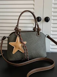Sac seau bandoulière vert texturé avec poignées marron et un charmant pendentif étoile.