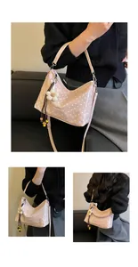 Detailed view of a trendy pink polka dot bucket bag with flower charm on model.