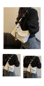 Detailed close-up view of a stylish white polka dot hobo bag with floral charm accessory