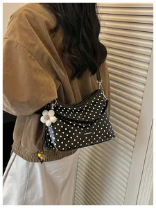 Side view of the black polka dot bucket bag with flower charm on a female model