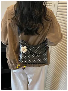 Detailed view of a black polka dot bucket bag with a white flower charm accessory.