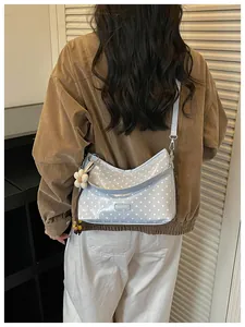 Rear view of model wearing a light blue polka dot bucket bag with a flower charm detail