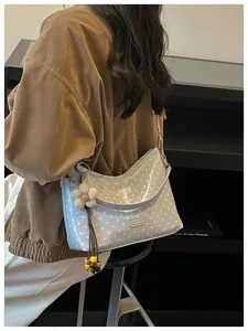 Detailed view of a light blue polka dot bucket bag worn elegantly as a shoulder bag