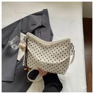 Detail view of white polka dot shoulder bag with cute flower charm and beads