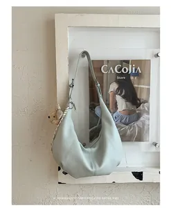 Minimalist light green ruched hobo bag hanging with a bear charm in retro decor.