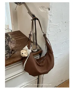 Brown pleated hobo bag with a cute bear charm hanging in a retro lifestyle setting