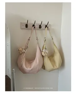 Minimalist pleated underarm hobo bags hanging in soft pink and yellow pastel colors.