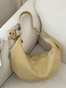 Elegant yellow hobo shoulder bag with a plush bear charm and grained leather texture