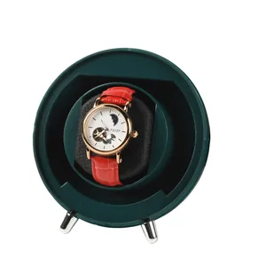 Detailed view of a dark green automatic watch winder holding a red luxury watch inside